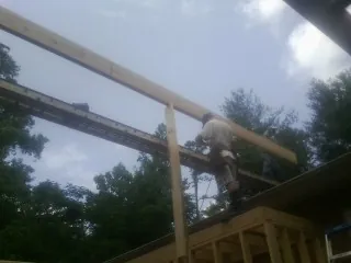 Carpenter setting a ridge beam over a new addition frame — Ice Dam Removal by Roofing Brothers in Deland
