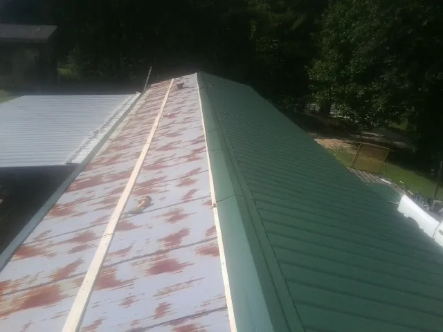 Old rusted panels beside newly installed green metal roofing — Wind Damage Roof Repair by Roofing Brothers in Deland