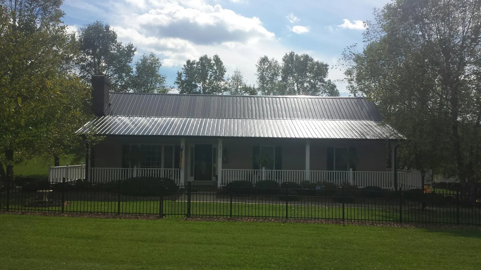 Gray metal roof on a brick ranch with a full width front porch — Gutter Guard Installation work by our crew in Deland