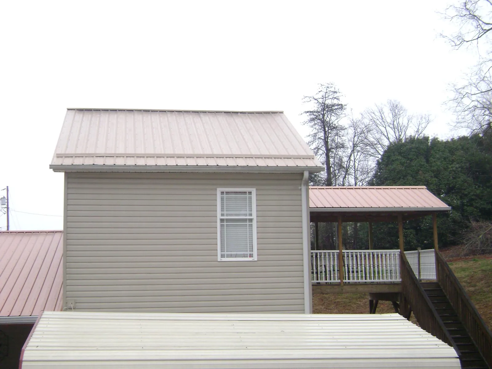Tan metal roofs on a two story addition and attached porch, from a Roof Replacement job in Deland
