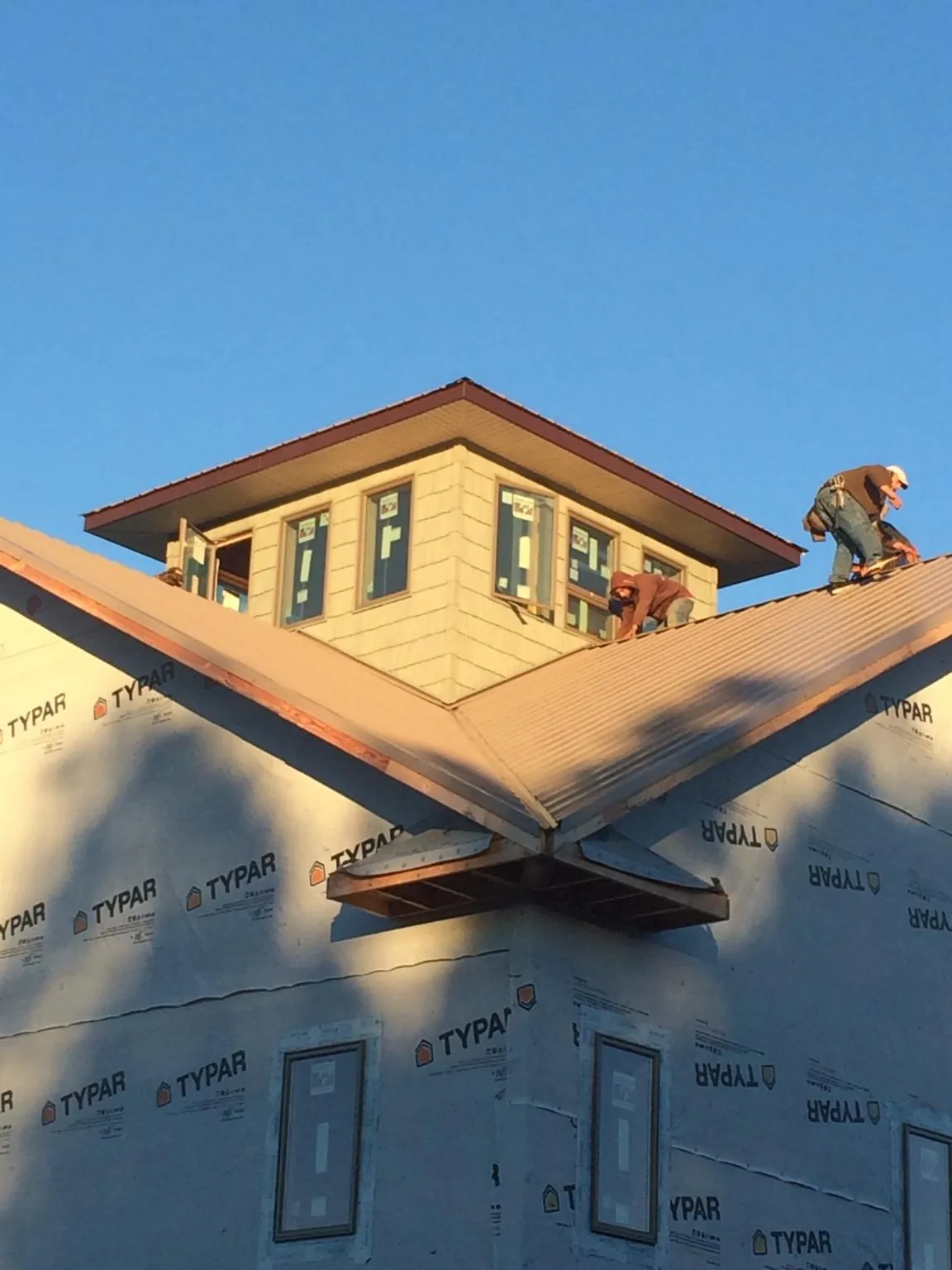 Roofers working around a rooftop cupola on a new metal roof at sunset — Roof Waterproofing in Deland by Roofing Brothers